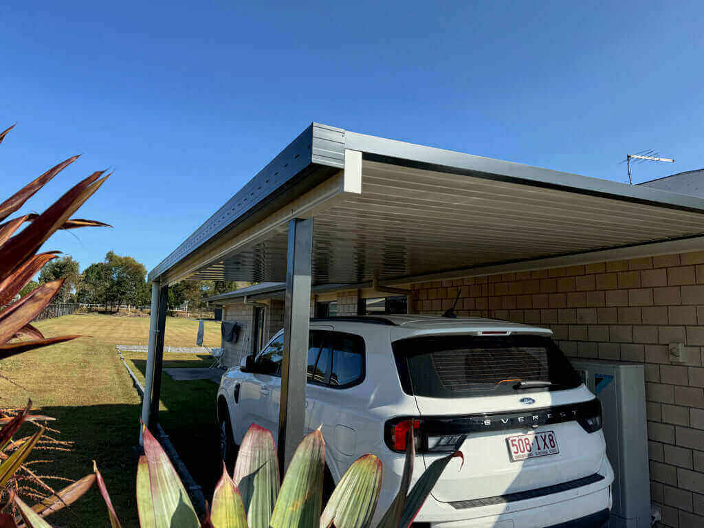 Single skin V-Line carport with a flat roof profile, attached to the home and supported by steel posts, providing a durable, low-maintenance carport solution that offers excellent vehicle protection, clean architectural lines, and a modern driveway upgrade suited to Australian conditions.