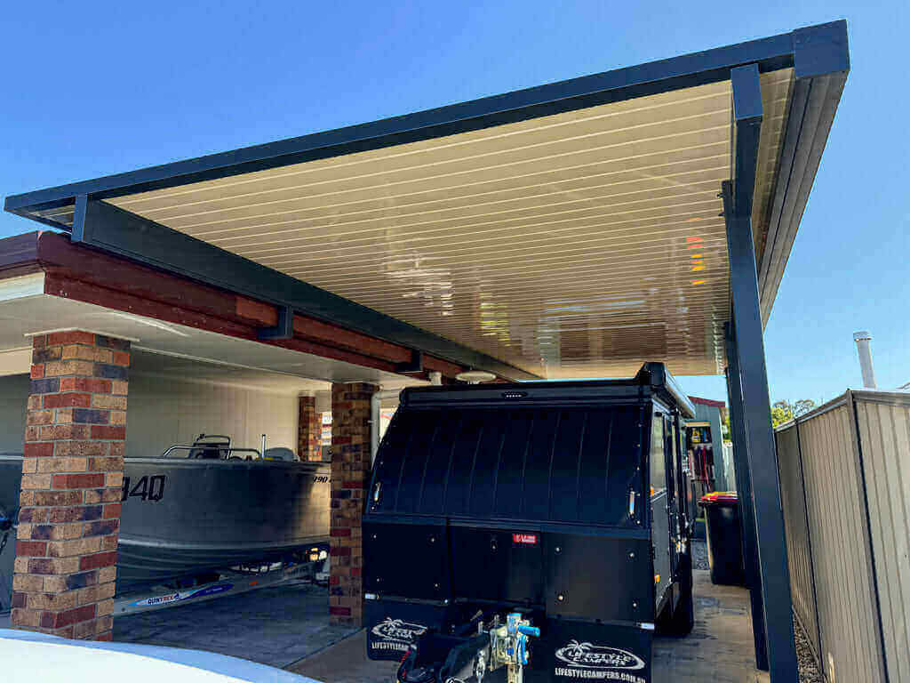 Modern single-skin patio carport with a streamlined roof design, seamlessly attached to the home to provide durable, weather-resistant covered parking and vehicle protection.