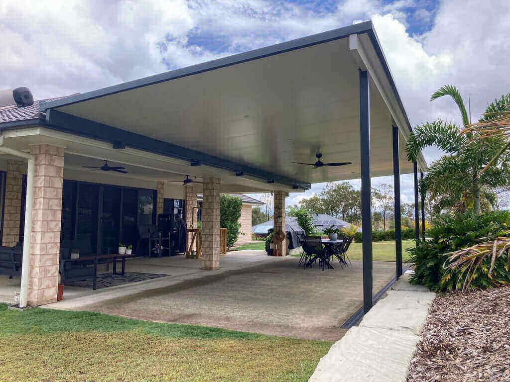 Elegant insulated flyover patio with upstand brackets, creating a stylish outdoor retreat complemented by a lush garden and picturesque views.
