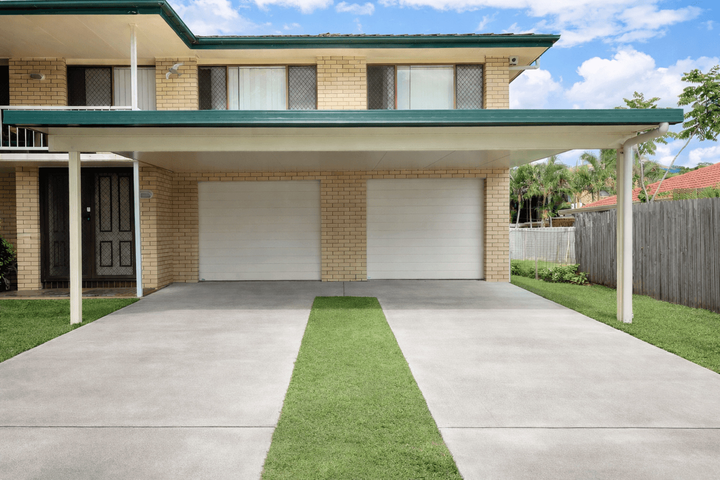 Insulated carport attached to brick house with double garage and wide concrete driveway