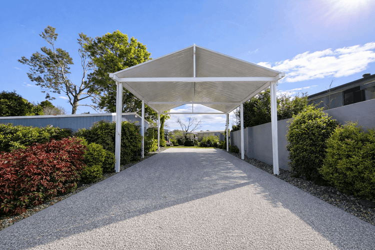 "White freestanding insulated diy car port kit with steel posts on a residential driveway"