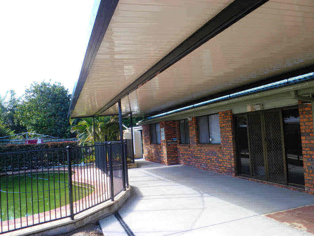 Single skin patio carport located in the pool area, perfectly complementing the surroundings and highlighting the pool for a cohesive and inviting outdoor space.