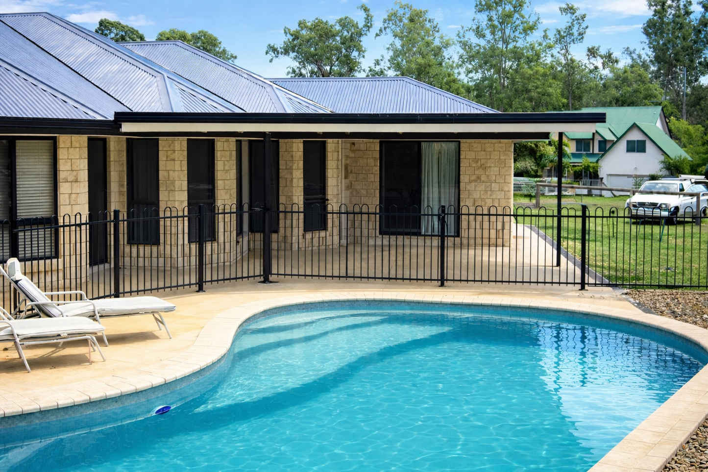 Modern covered patio roof attached to a brick house overlooking a backyard pool and outdoor entertaining area.