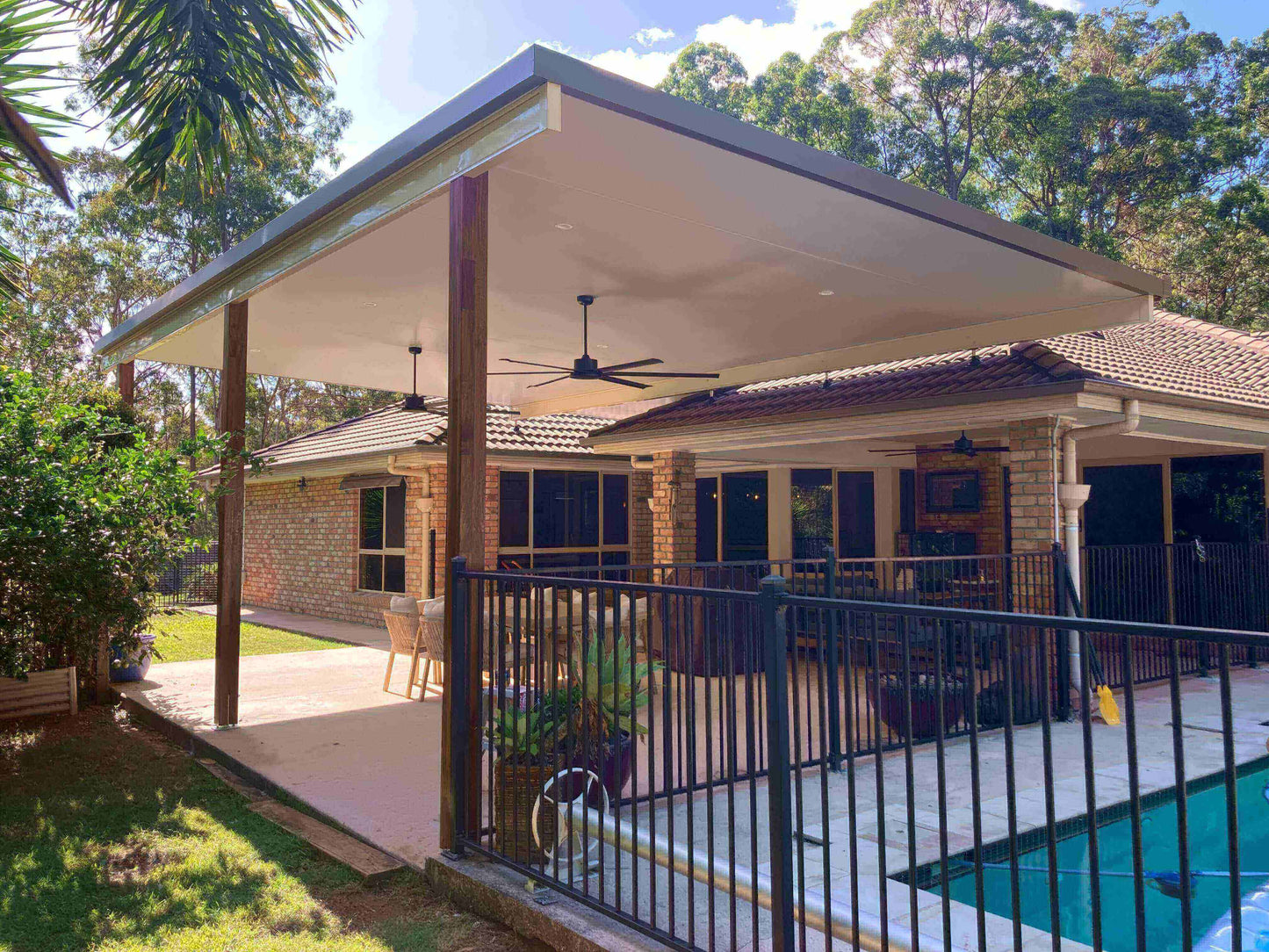 Cozy outdoor retreat with insulated flyover patio and carport, ceiling fan, and stylish garden-focused design.