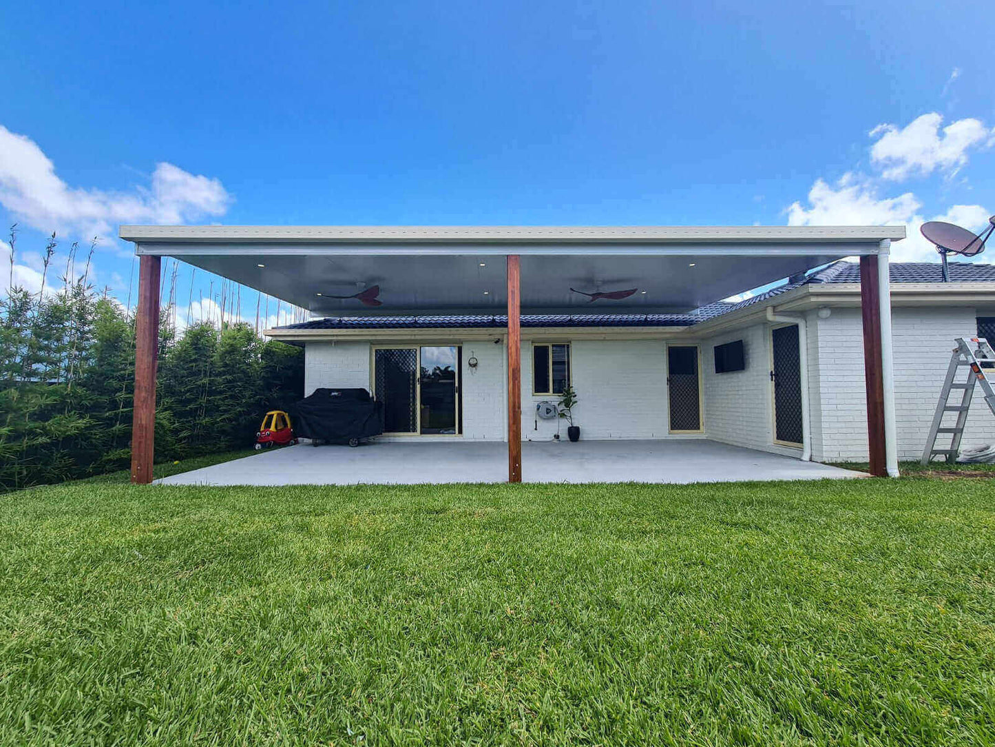 Functional and stylish insulated flyover patio and carport with timber posts, complemented by well-maintained green turf for outdoor enjoyment.
