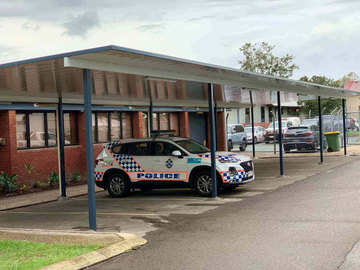 Free standing single skin patio carport designed for a commercial police station, offering durable weather protection for the fleet of service vehicles.