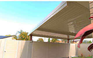 Single skin patio roof attached to a house wall, providing shaded outdoor space with a simple and durable steel design.