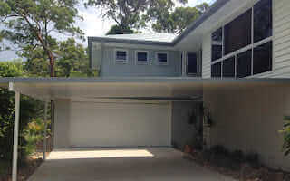 Attached insulated carport with sleek design, providing shelter for vehicles next to a modern home.