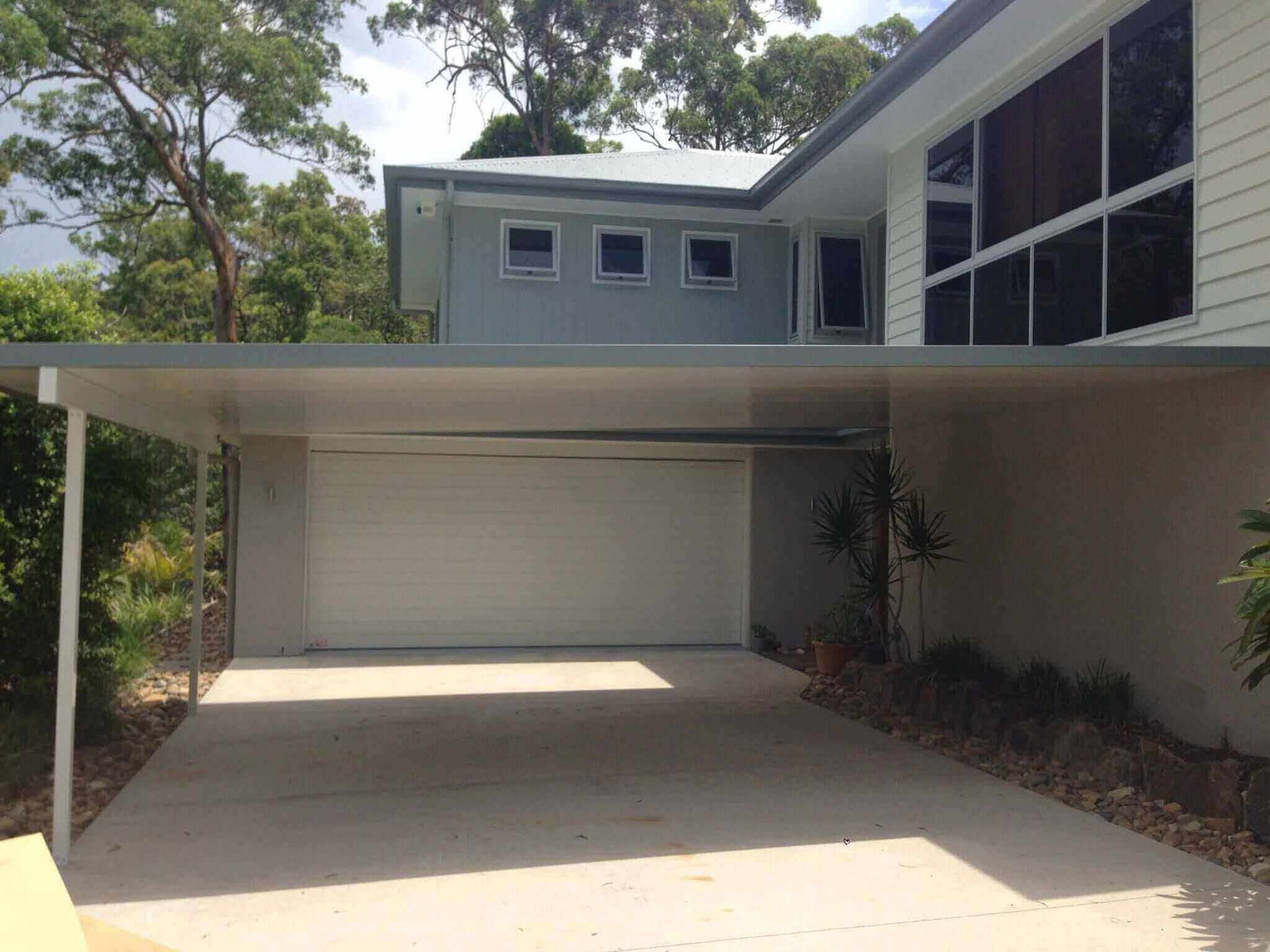 Insulated patio roof attached to a double garage, providing sheltered carport space and weather protection at a modern home.