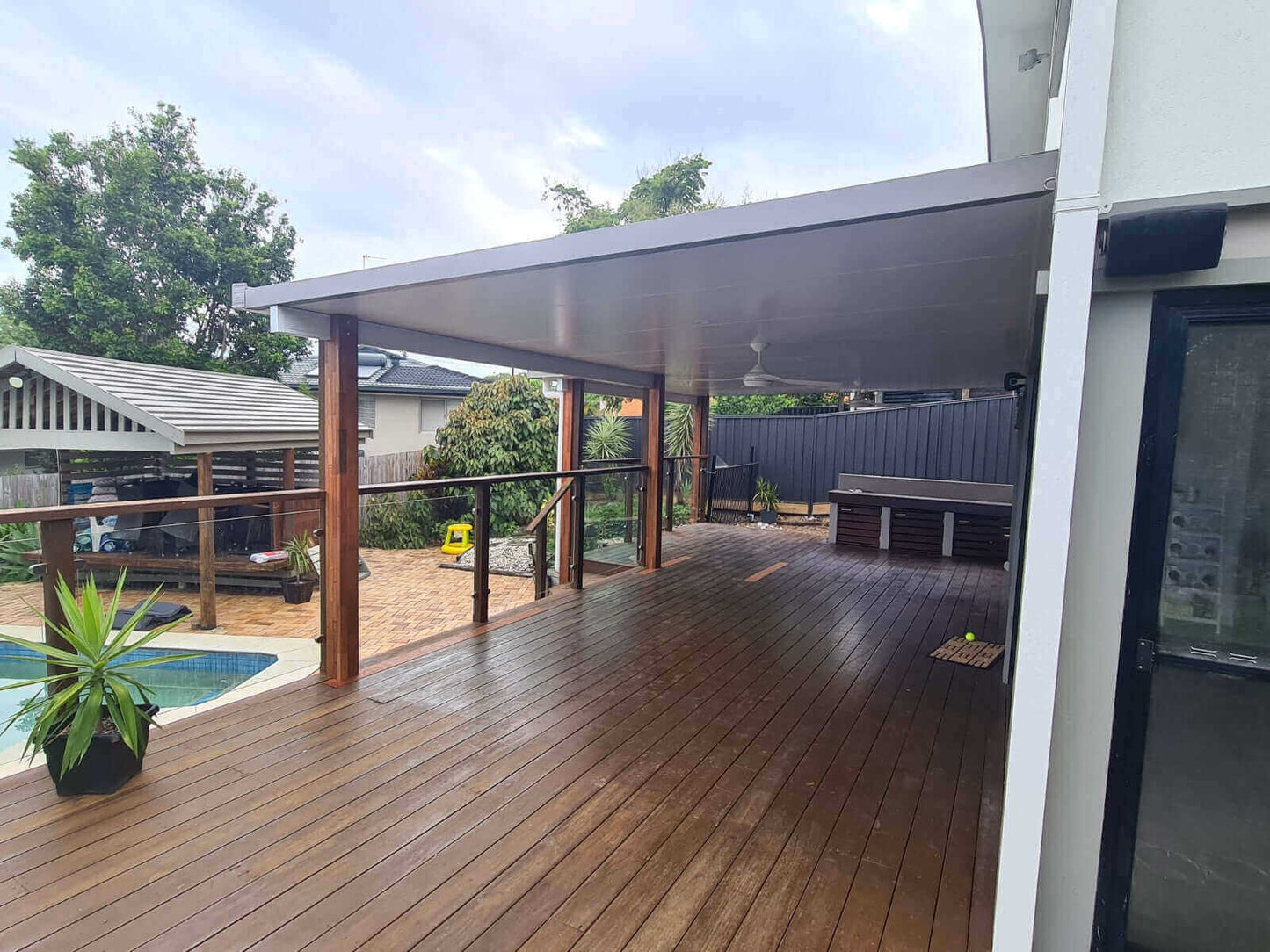 Spacious insulated patio with timber posts overlooking a pool area, ideal for relaxing and entertaining.