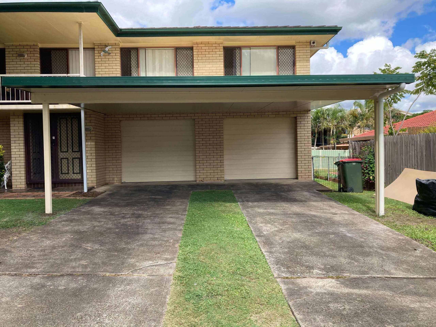 Attached insulated carport featuring two garage doors, set over a concrete driveway with an adjacent grassy area for a balanced, functional look.