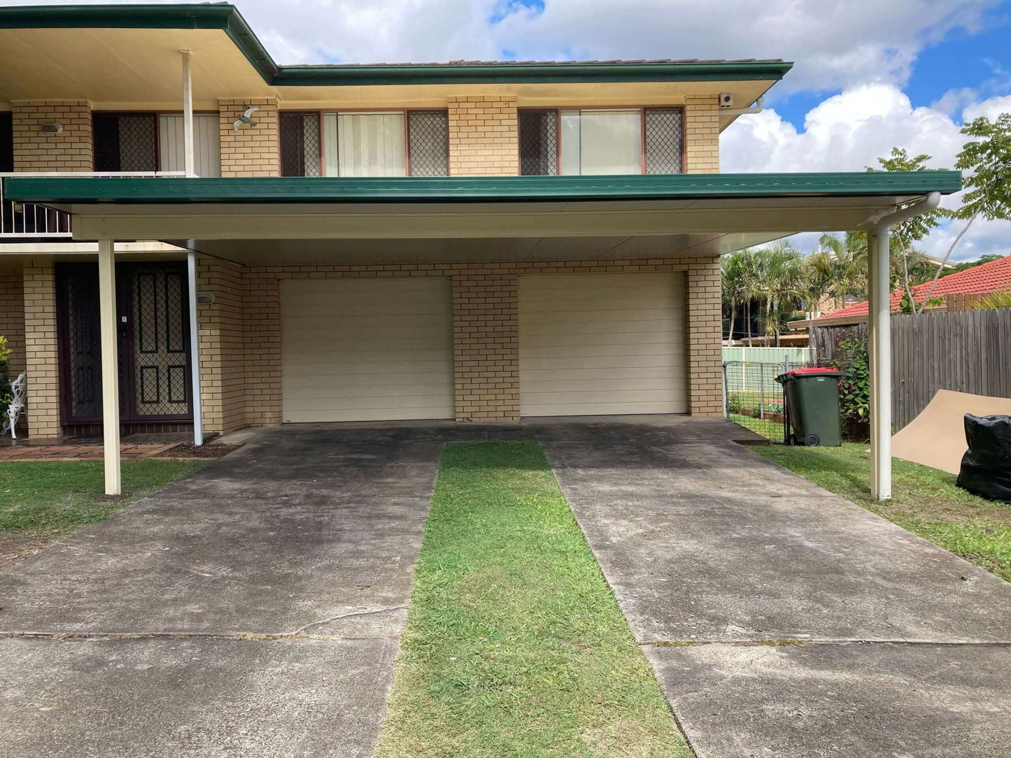 Insulated patio and carport with metal fascia, providing shade for driveway and garage doors.