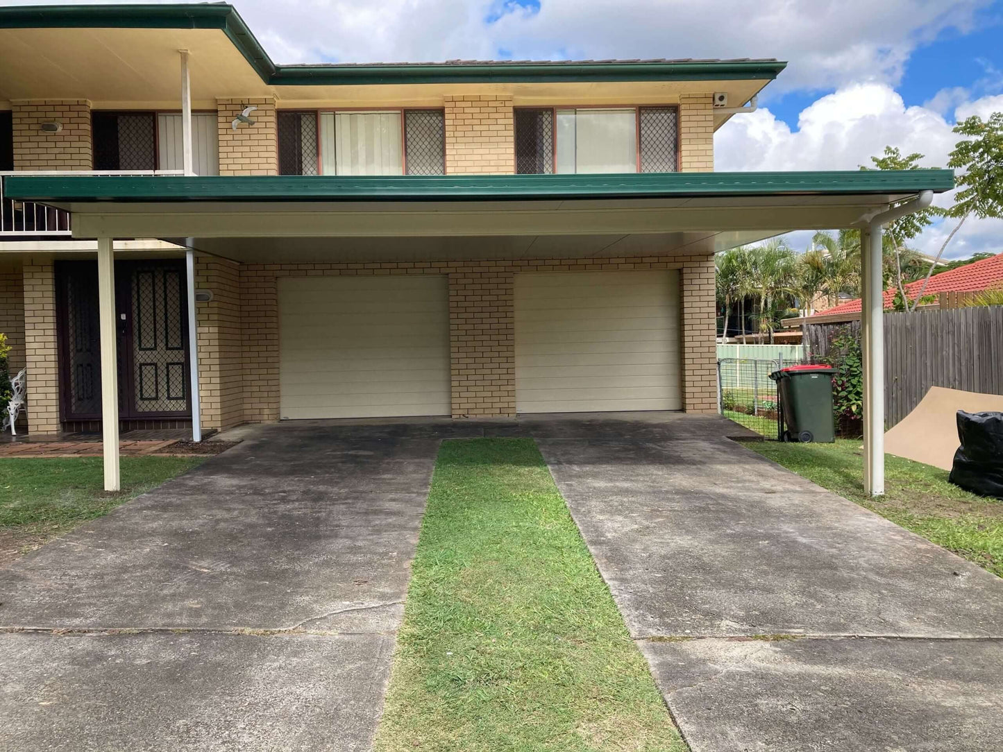 Attached insulated patio carport with concrete driveway and dual garage doors.