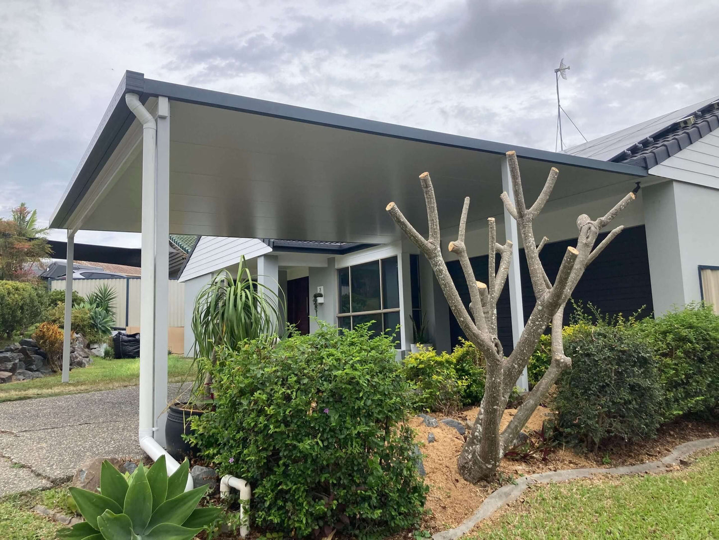 Attached insulated patio carport with metal fascia and landscaped garden exterior.