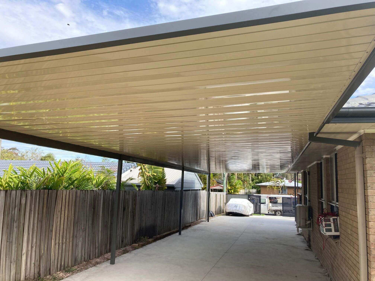 Single skin V-Line carport roof attached to house with steel posts, providing modern carport roofing and covered driveway parking for an Australian home.
