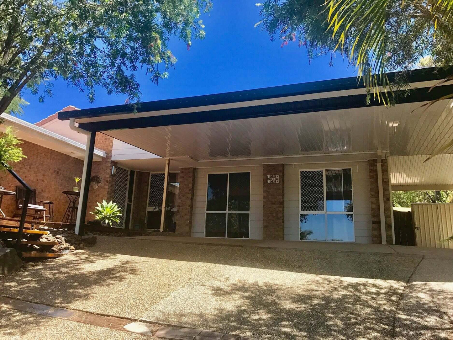 Single skin V-Line flat roof patio attached to house with steel posts and modern patio roofing, creating a shaded outdoor living area for an Australian home.