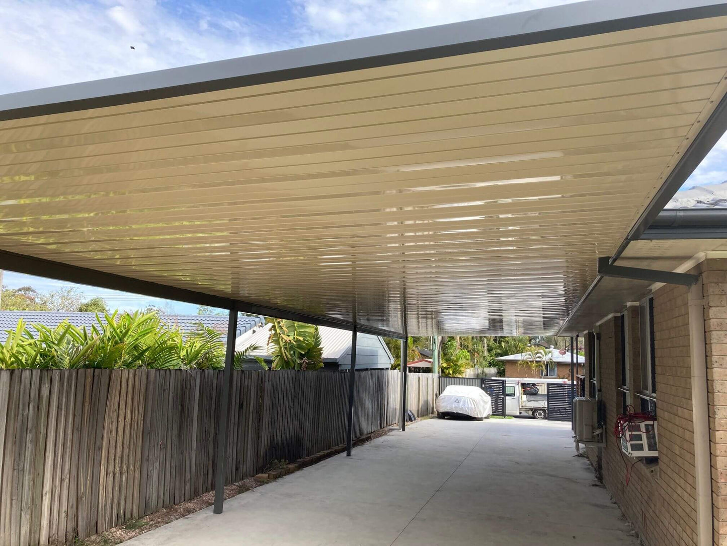 Single skin V-Line carport roof attached to house with steel posts, providing modern carport roofing and covered driveway parking for an Australian home.
