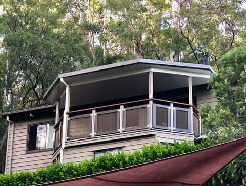Modern house with metal fascia featuring a spacious outdoor patio surrounded by greenery.