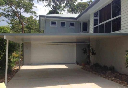 Attached insulated patio and carport featuring sleek design and concrete wall, providing weather resistance and year-round comfort.