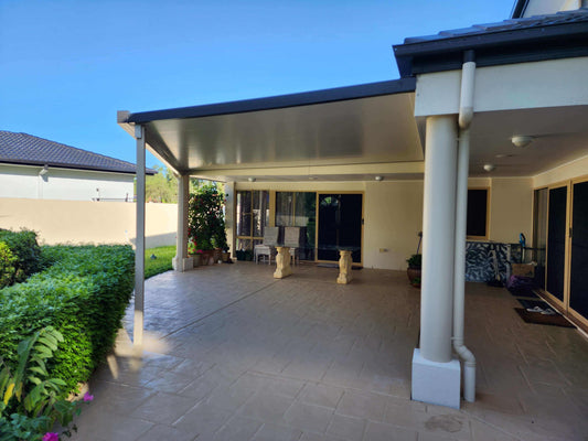 Modern insulated patio roof attached to a home, providing a weather-protected outdoor seating area and garden view.