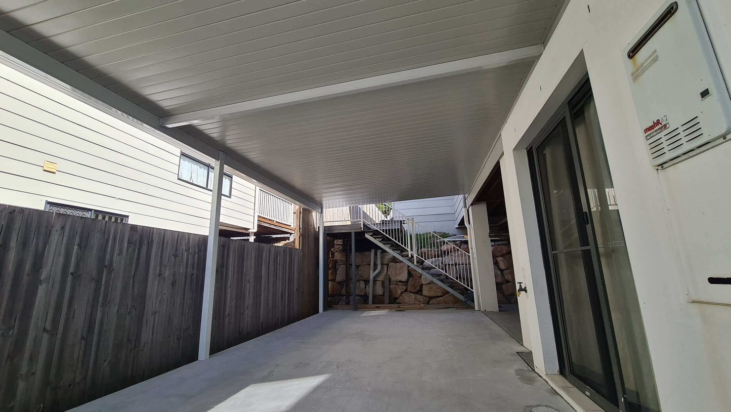 Attached single skin patio carport providing sheltered parking space beside a home, protecting vehicles from weather.
