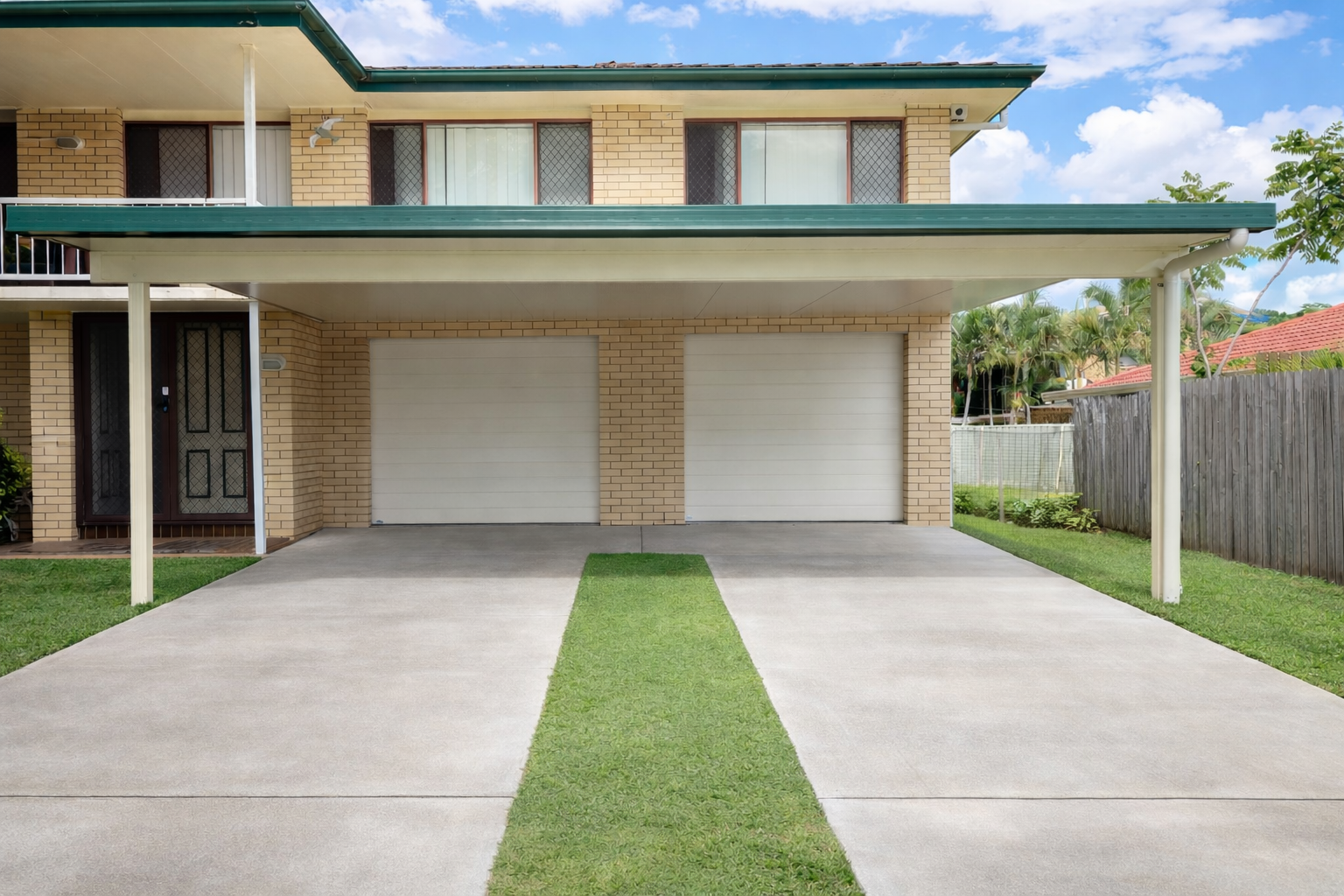Insulated carport attached to brick house with double garage and wide concrete driveway