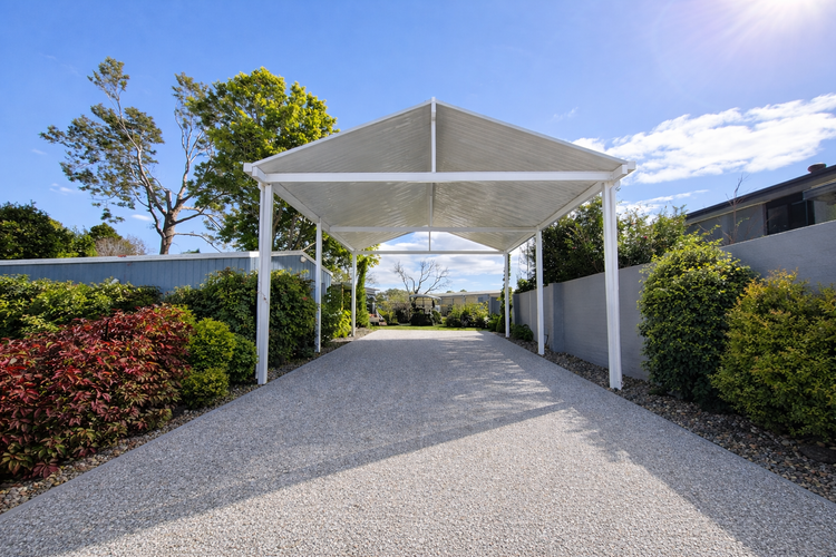"White freestanding insulated diy car port kit with steel posts on a residential driveway"
