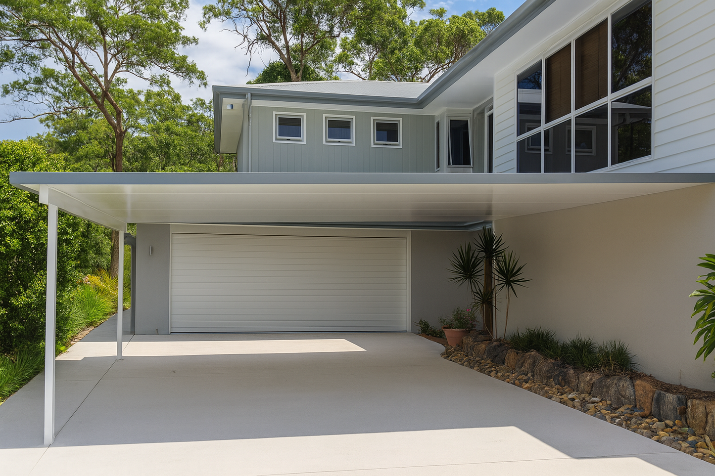 Modern insulated patio roof fixed to wall of a suburban home, featuring a sleek flat design with clean white soffit panels and slim support posts, extending over a concrete carport area.