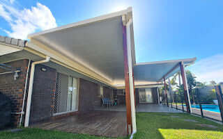 Outdoor insulated patio and carport with wooden supports and ribbed roof, combining elegance and functionality.