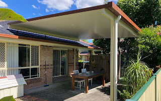 Stylish flyover patio roof in manor red with insulation, offering shade and shelter from harsh weather while enhancing backyard aesthetics.