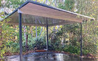 Free-standing patio carport nestled in natural surroundings, providing a comfortable outdoor space to relax while offering reliable shelter in any weather.