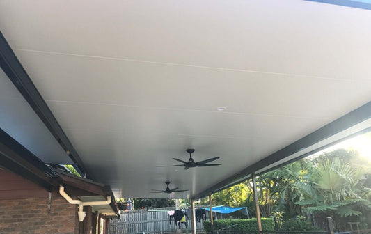 Close-up view of an insulated patio roof with integrated ceiling fans and recessed lighting, offering cool and comfortable outdoor living space.