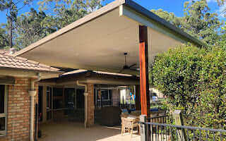 Elevated insulated patio carport flyover, featuring a ribbed roof and timber pillars that bring warmth and character to any outdoor setting.