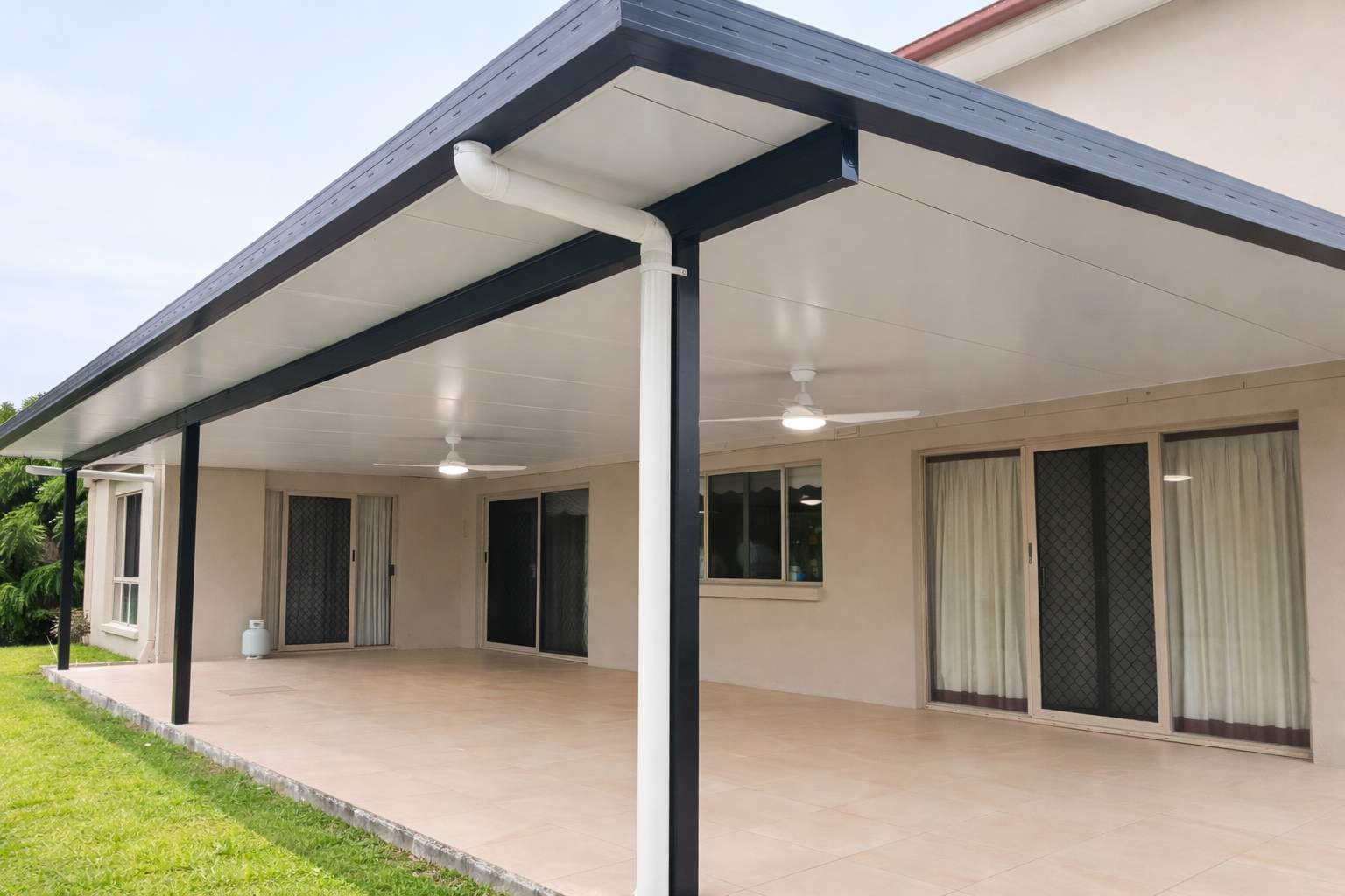 Insulated patio roof with black steel posts and white ceiling panels attached to modern home