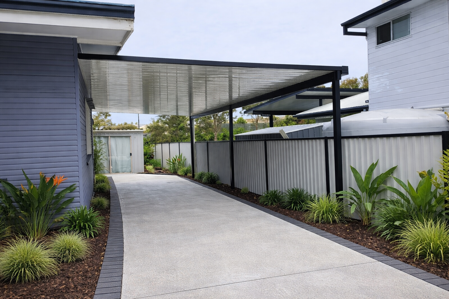 Modern flat-roof, single-skin patio/carport roofing, fixed to wall. Supported by black steel beams. 