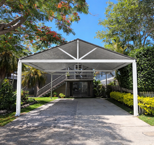 Large freestanding gable carport with a white steel frame and V-line metal roofing, providing wide-span vehicle coverage and a modern finish.