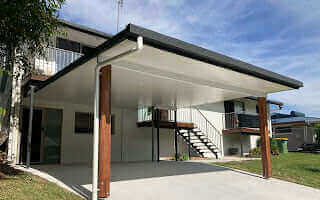 Insulated carport extension attached to a two-storey home with timber posts, offering sheltered parking and outdoor living space.
