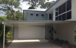 Insulated carport patio attached to a rendered wall, combining modern lines and durable materials for all-weather protection.
