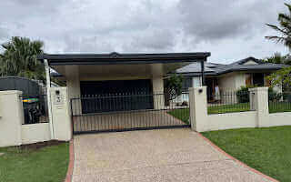 Sleek modern single skin carport with a flat roof seamlessly extending over the driveway, offering stylish cover to a double garage in a contemporary home setting.