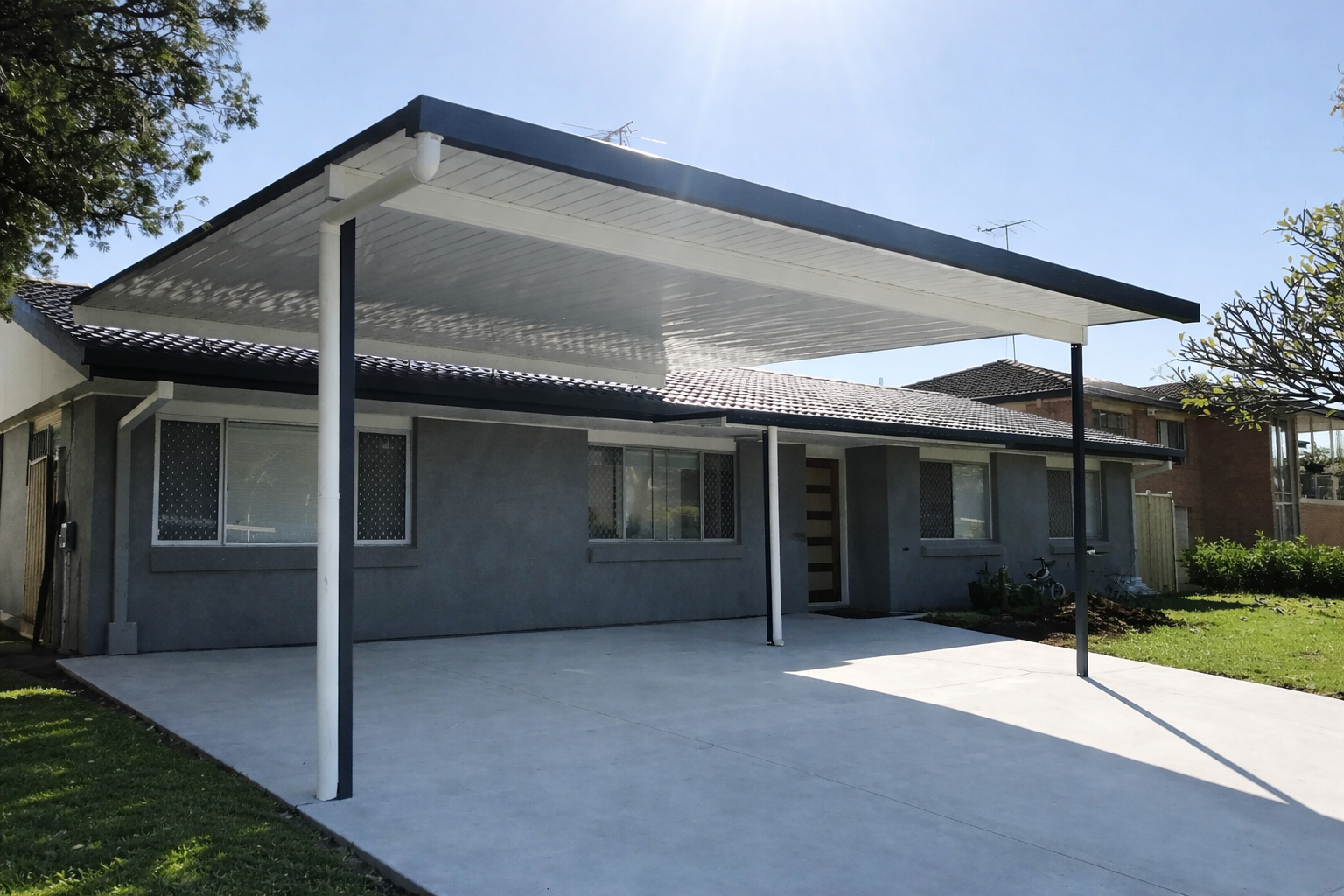 Modern single-skin flyover carport with a flat white roof and contrasting dark frame, installed over a concrete driveway
