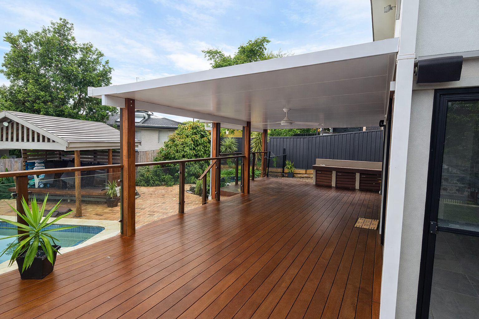 Modern insulated patio roof with sleek white ceiling panels supported by timber posts over a spacious wooden deck