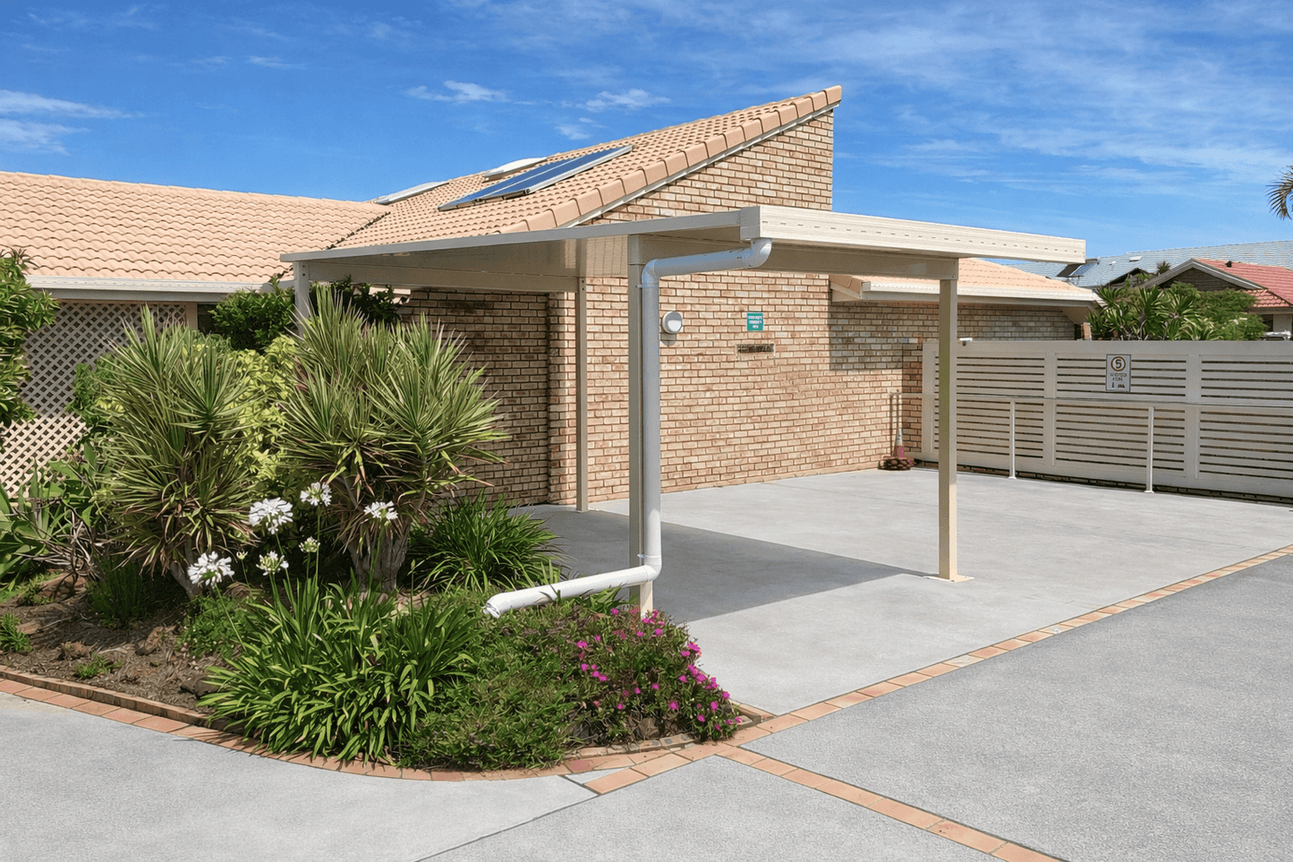 Modern freestanding single-skin carport with cream steel posts and flat roof